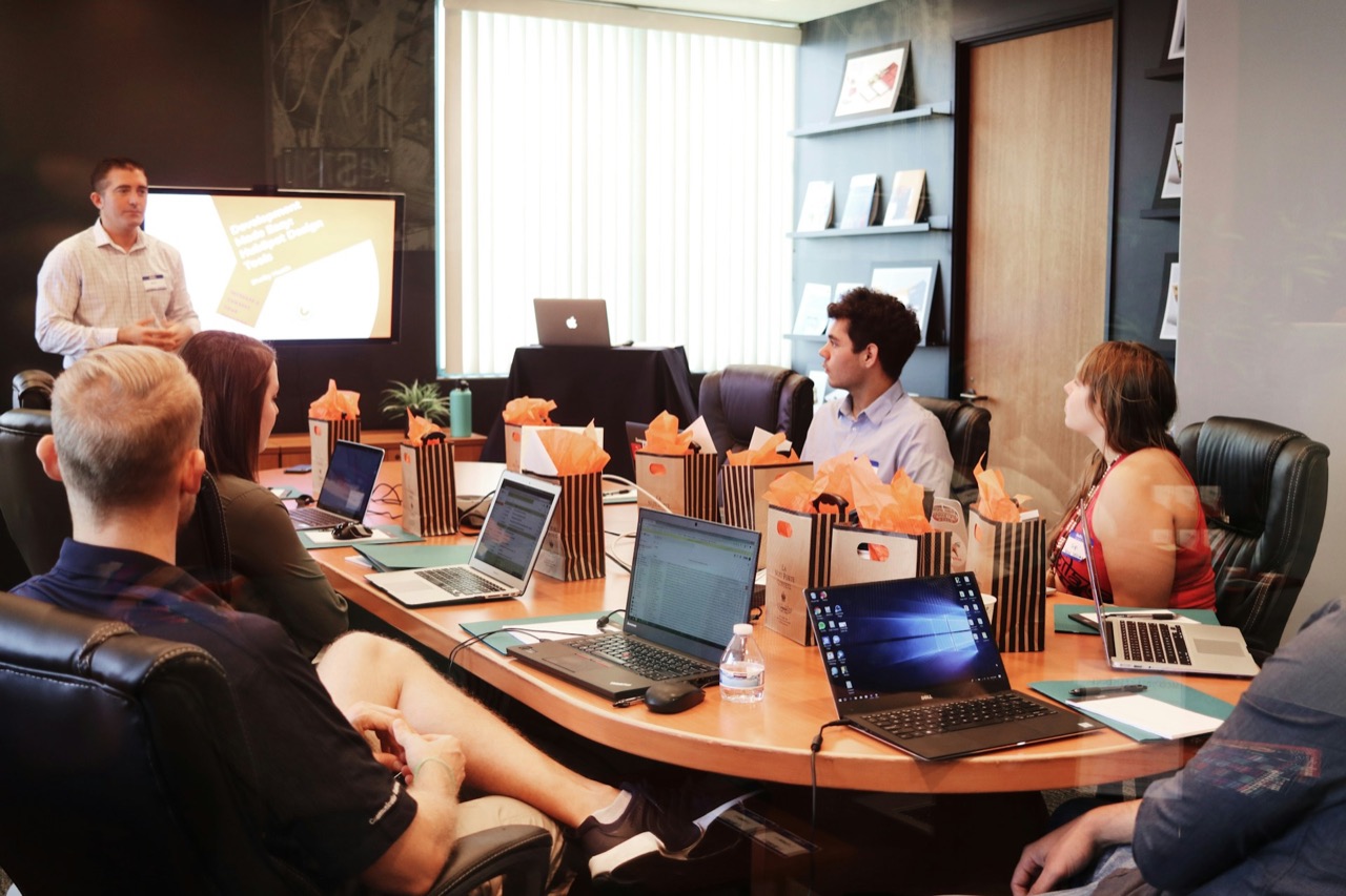 Trainer leading a session for staff working on laptops around a conference table